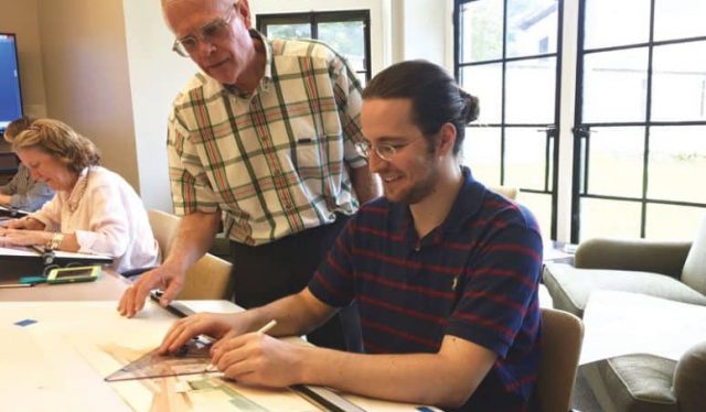 Professor Robert Hardy with student Timothy Beaupre. Student is working on an interior design on a drafting table.